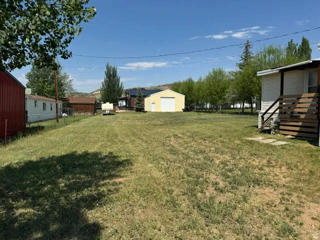 Expansive grassy yard area with a detached yellow garage featuring a white overhead door