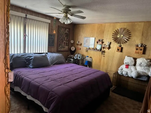 Bedroom featuring wood paneling, a ceiling fan with integrated lighting, and vertical blinds on the window