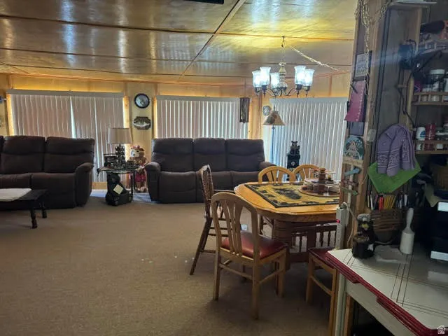 Open-concept living space featuring wood-paneled ceiling, neutral carpeting, and multiple vertical blinds