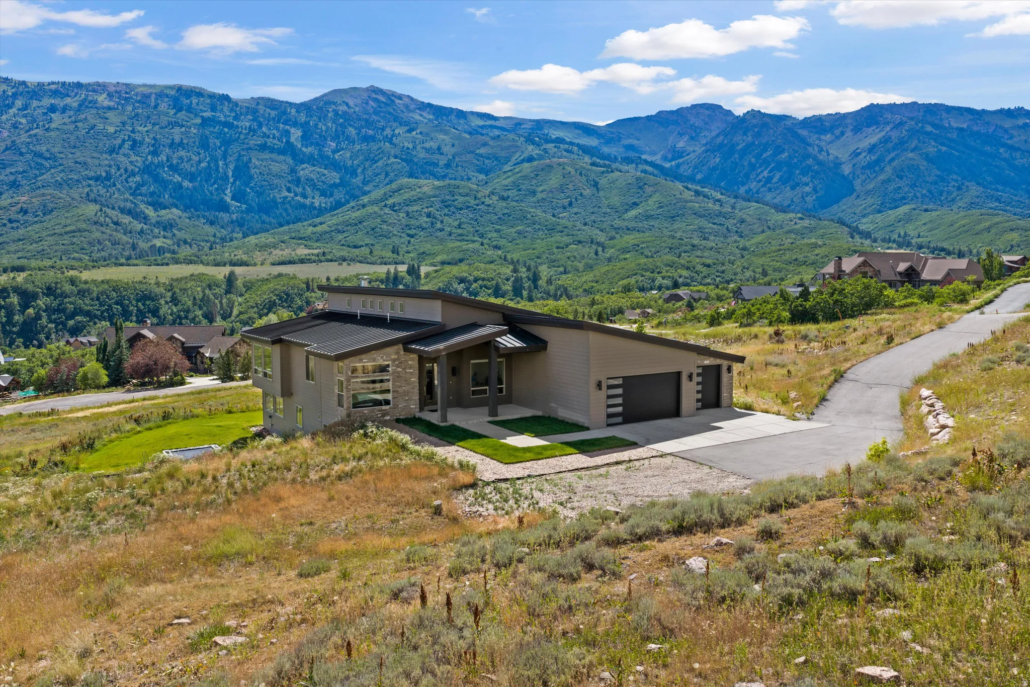 Contemporary architecture featuring a stone and stucco exterior, a multi-car garage, and a sloped roofline
