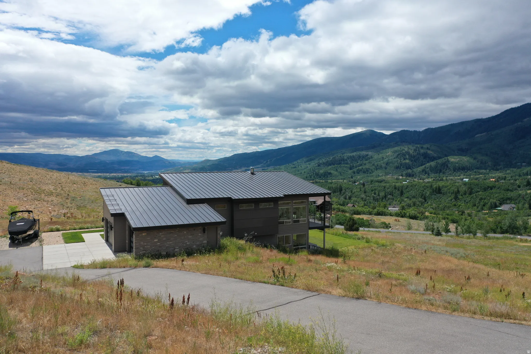 Modern-style residence featuring a metal roof, a blend of horizontal siding and stone accents, and expansive windows