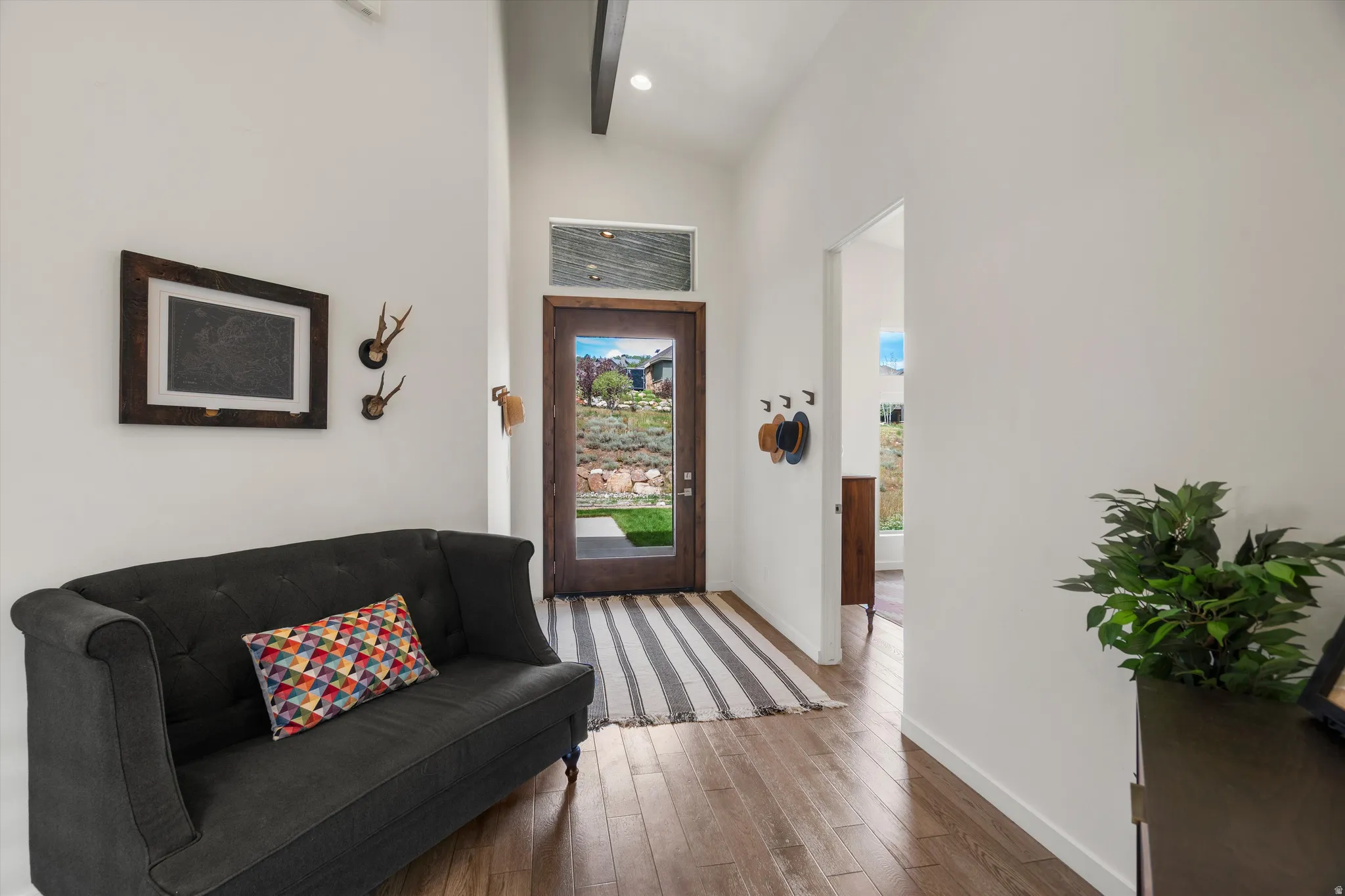 Entryway featuring wood-finish flooring, a full-lite door with transom window, and high ceilings with exposed beams
