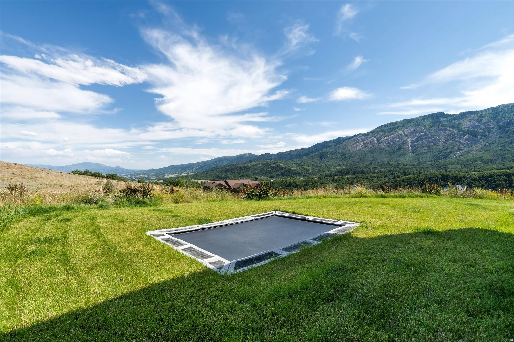 Expansive grassy lawn featuring a built-in rectangular trampoline