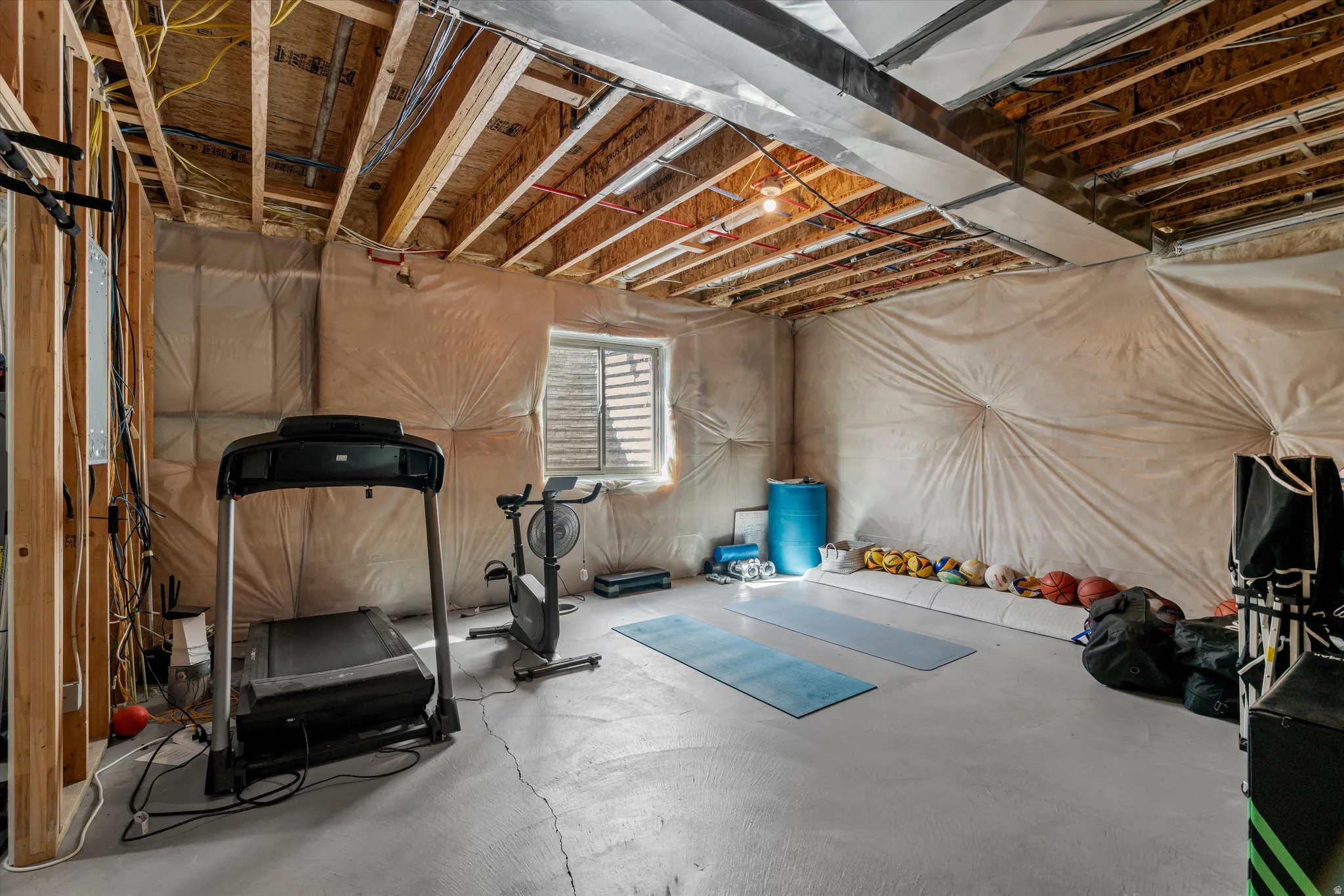 Unfinished basement with exposed ceiling joists and concrete flooring