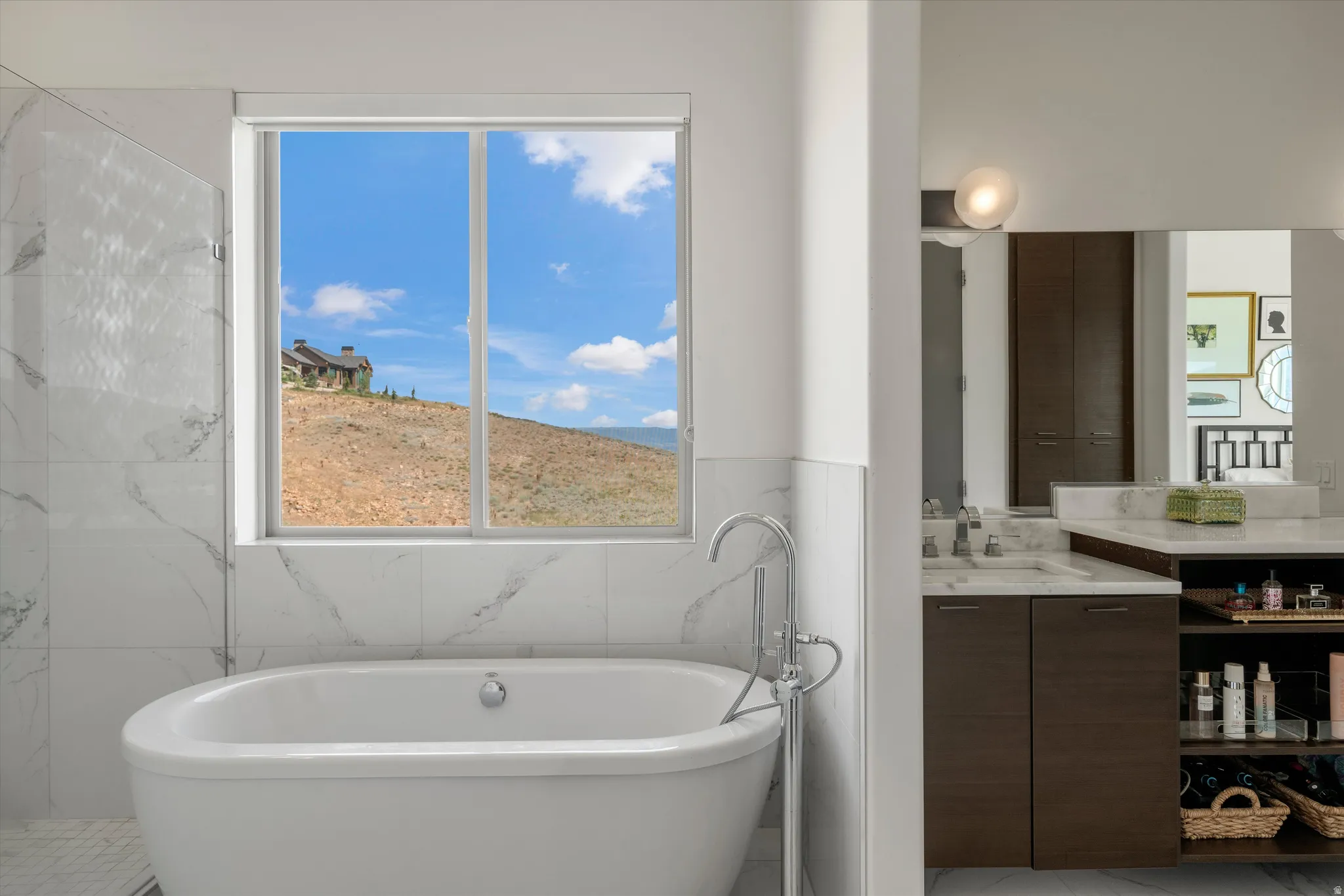 Freestanding soaking tub with a floor-mounted chrome faucet, set against a window