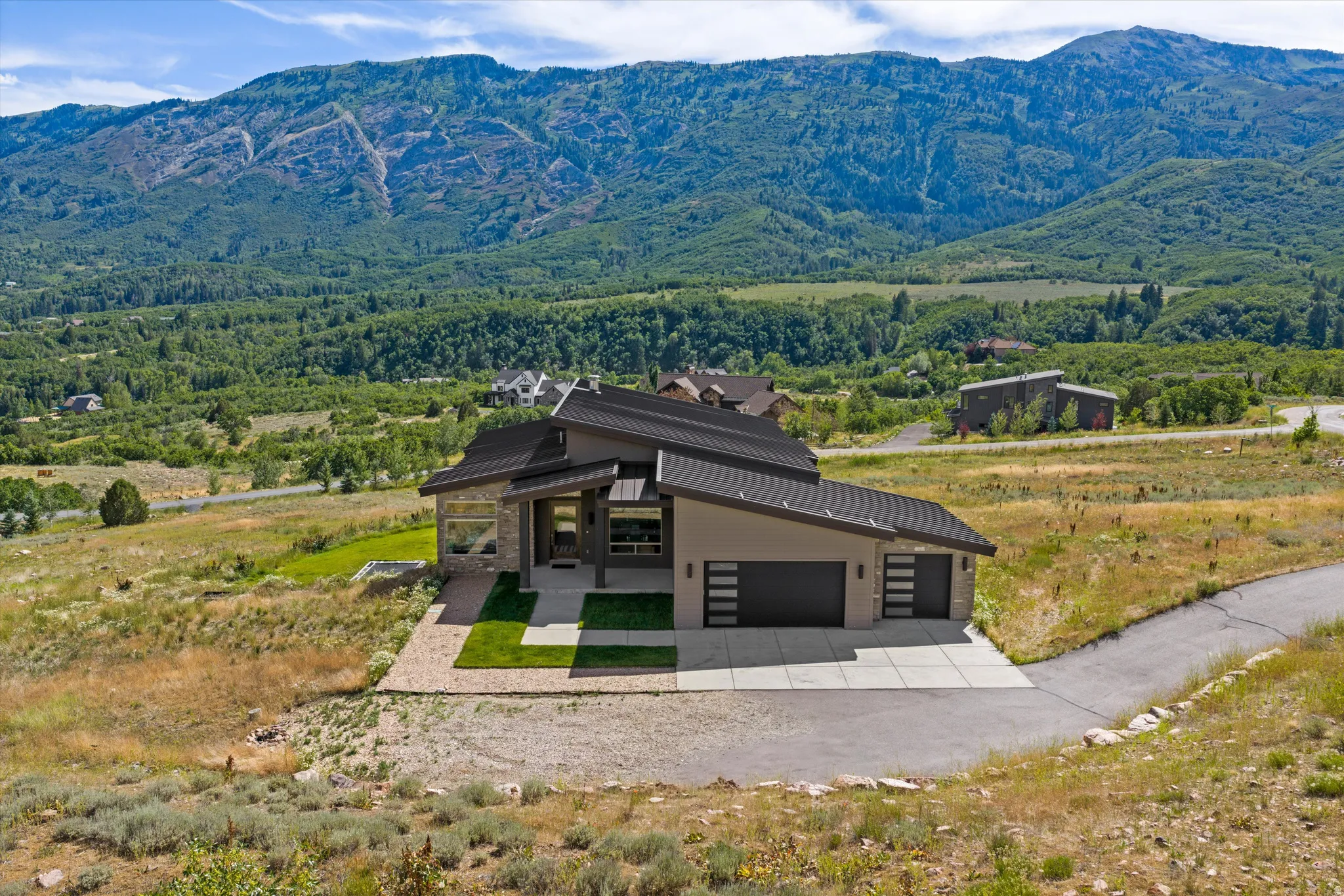 Contemporary architectural design featuring a multi-pitched roofline, an attached two-car garage, and a large concrete driveway