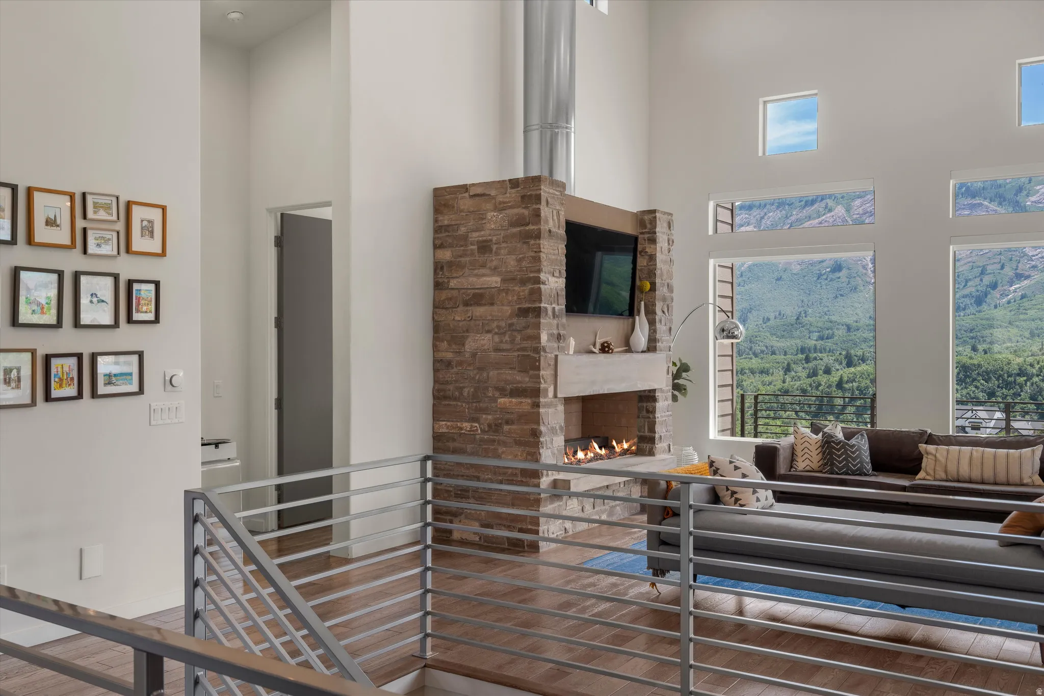 Spacious living area featuring high ceilings, a stone-clad fireplace, and extensive window walls