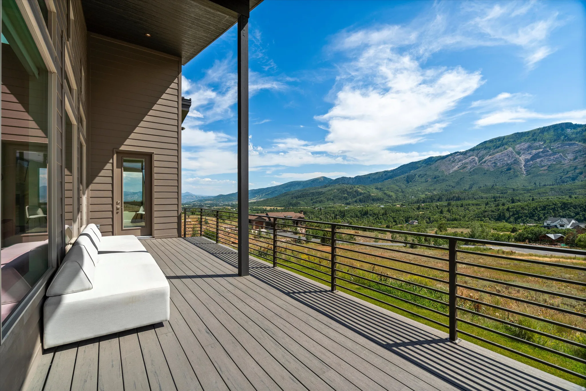 Spacious elevated deck featuring composite decking, horizontal metal railings, and a direct mountain backdrop
