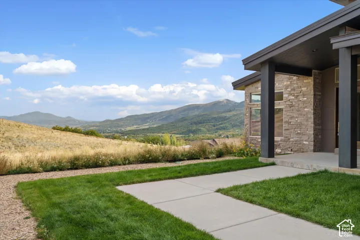 Stone exterior with contemporary columns, concrete entryway, and manicured lawn