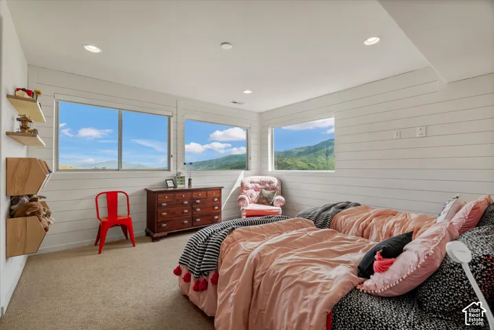 Carpeted room featuring horizontal shiplap walls, recessed ceiling lighting, and multiple windows showcasing a mountainous landscape