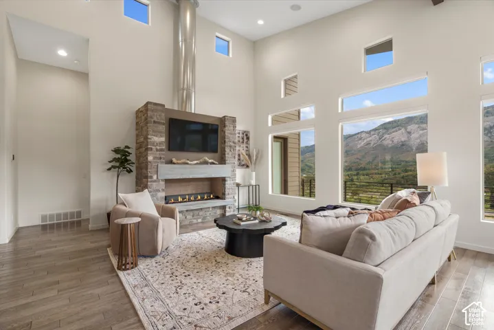 Vaulted ceilings with recessed lighting, floor-to-ceiling stone-clad fireplace, linear gas fireplace, and wood-finish flooring