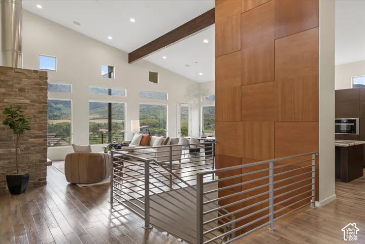 Vaulted ceiling with exposed wood beam, full-height stone-clad column, wood-finish flooring, and multi-pane windows