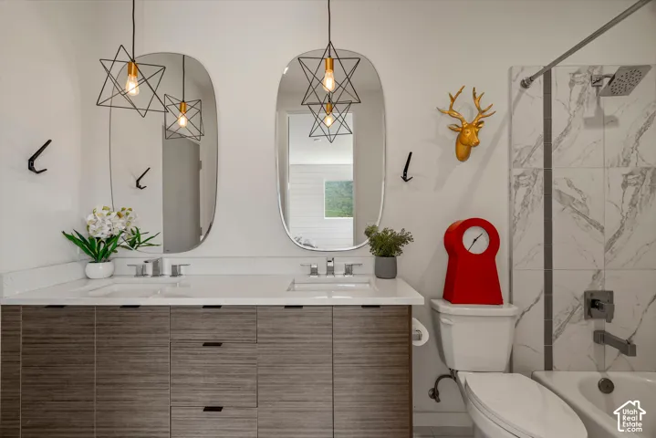 Dual vanity with integrated sinks and wood-finish cabinetry, illuminated by two geometric pendant lights