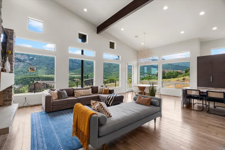 Great room featuring a vaulted ceiling with exposed beam, expansive windows, recessed lighting, and wood-finish flooring