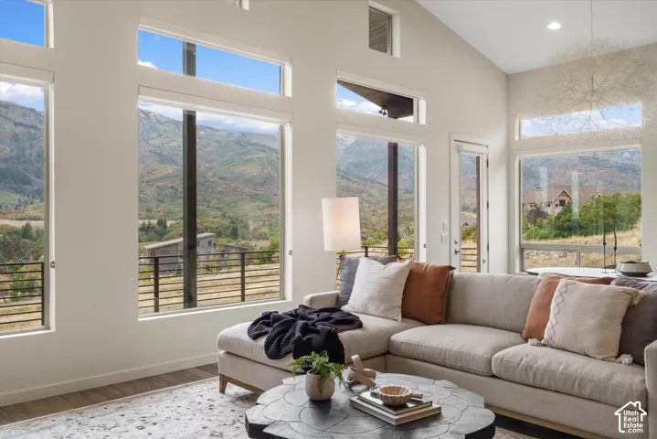 Vaulted ceiling, multiple large windows, wood-finish flooring, recessed lighting, and a door with glass panels