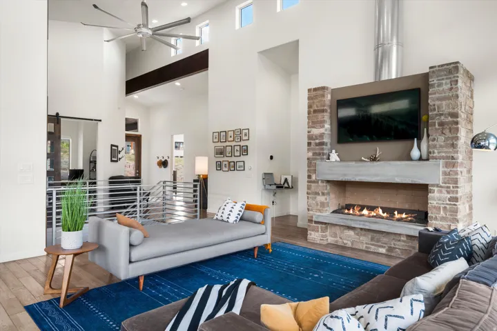 Two-story living area featuring a stone-clad fireplace with a concrete mantel