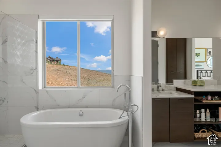Freestanding soaking tub with a floor-mounted chrome faucet, set against a window