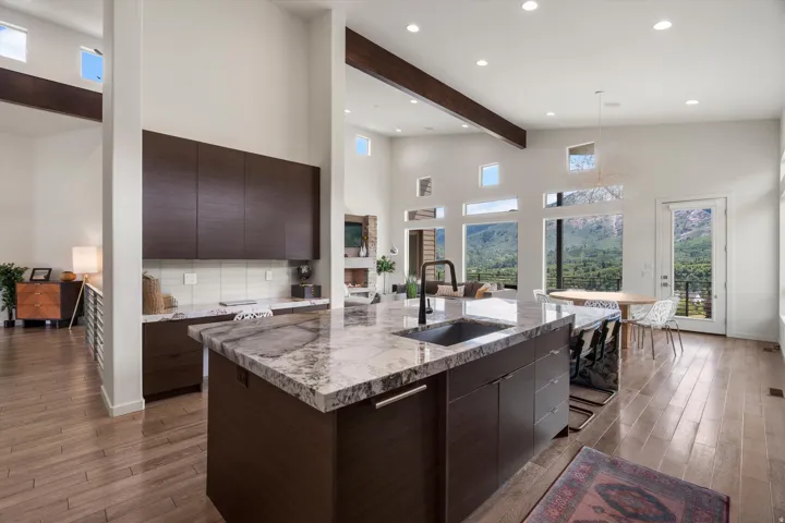 Spacious kitchen featuring a large island with an undermount sink, dark wood cabinetry, and light wood-finish flooring