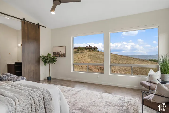 Vaulted ceiling with a contemporary ceiling fan, wood-finish flooring, and large windows showcasing a distant natural landscape