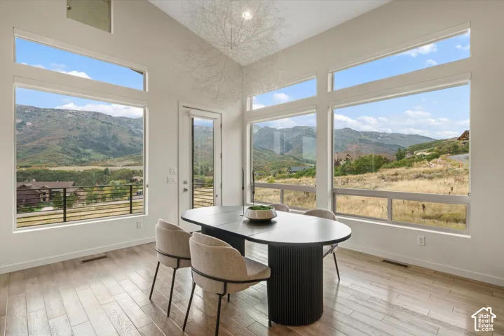 Expansive windows framing mountain and distant water scenery, tall ceilings, and wood-finish flooring