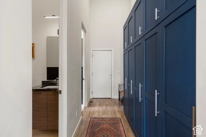 Hallway featuring floor-to-ceiling blue cabinetry with silver hardware, wood-finish flooring, and a high ceiling
