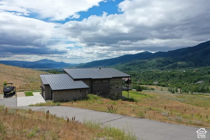 Modern-style residence featuring a metal roof, a blend of horizontal siding and stone accents, and expansive windows