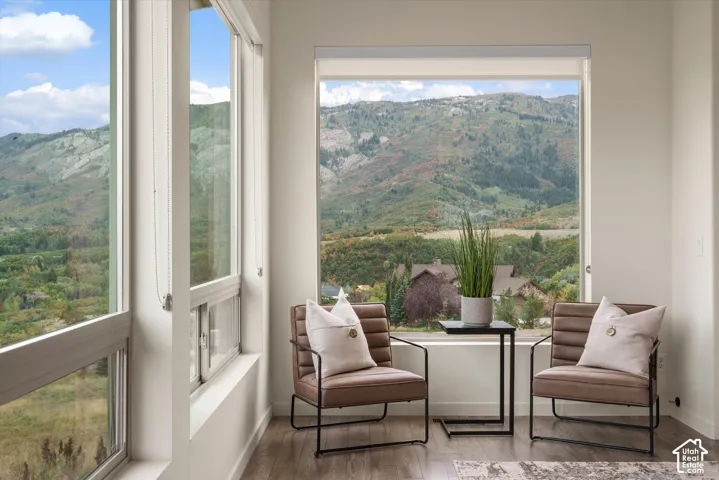 Floor-to-ceiling windows, mountain scenery, light wood-finish flooring, white walls, built-in window shade