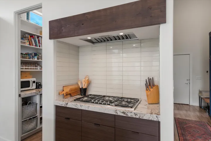 Modern kitchen featuring a gas range, white subway tile backsplash, and a built-in stainless steel range hood