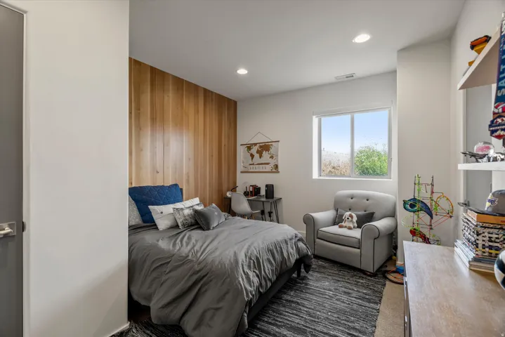 Bedroom featuring a wood accent wall, recessed lighting, and a single window with outdoor scenery