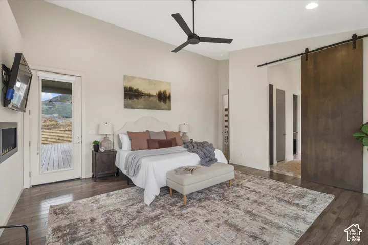 Vaulted ceiling with a black ceiling fan, wood-finish flooring, built-in fireplace, and a barn door entry
