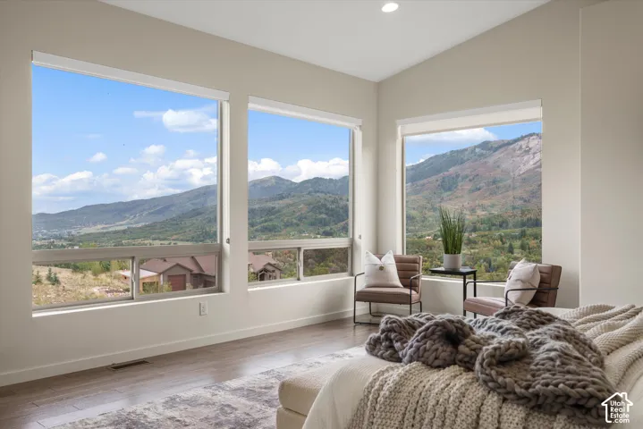 Expansive windows offering mountain scenery, wood-finish flooring, vaulted ceilings, and recessed lighting