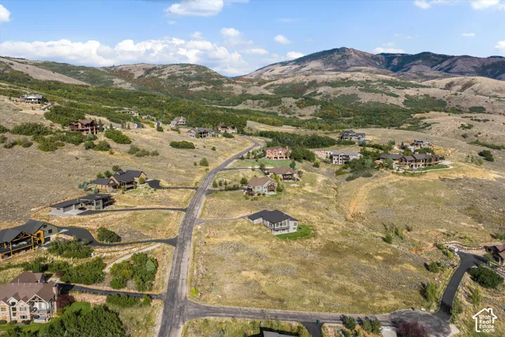 Expansive mountain landscape featuring varied terrain and scattered residential properties, with paved roads providing access to individual homes