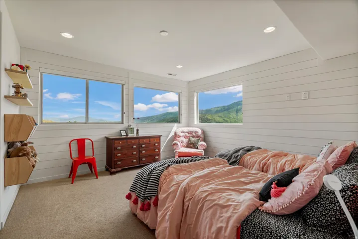 Carpeted room featuring horizontal shiplap walls, recessed ceiling lighting, and multiple windows showcasing a mountainous landscape