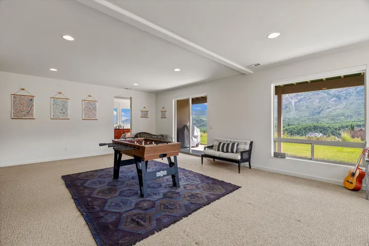 Expansive recreation room featuring recessed lighting, a sliding glass door, and a large window presenting mountainous scenery