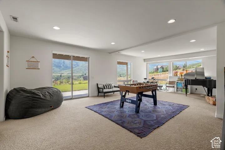 Spacious lower-level room featuring large sliding glass doors, multiple windows, recessed lighting, and soft carpet flooring