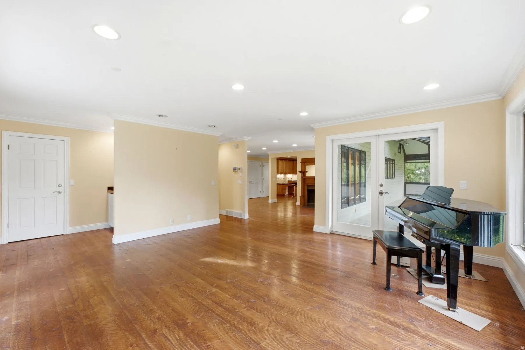 Recessed lighting, crown molding, wood-finish flooring, white paneled doors, and French doors leading to an exterior space