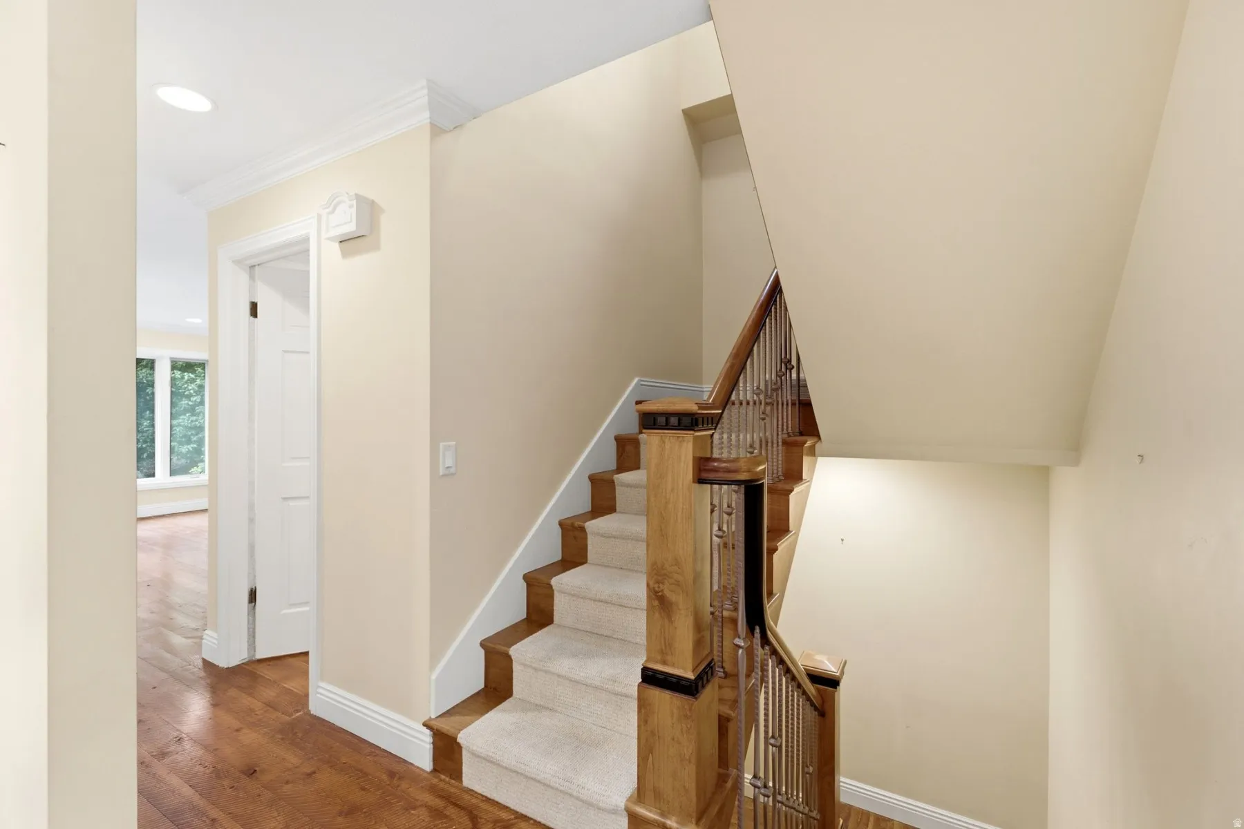 Staircase with wood treads and carpet runner, featuring wood newel posts and iron balusters