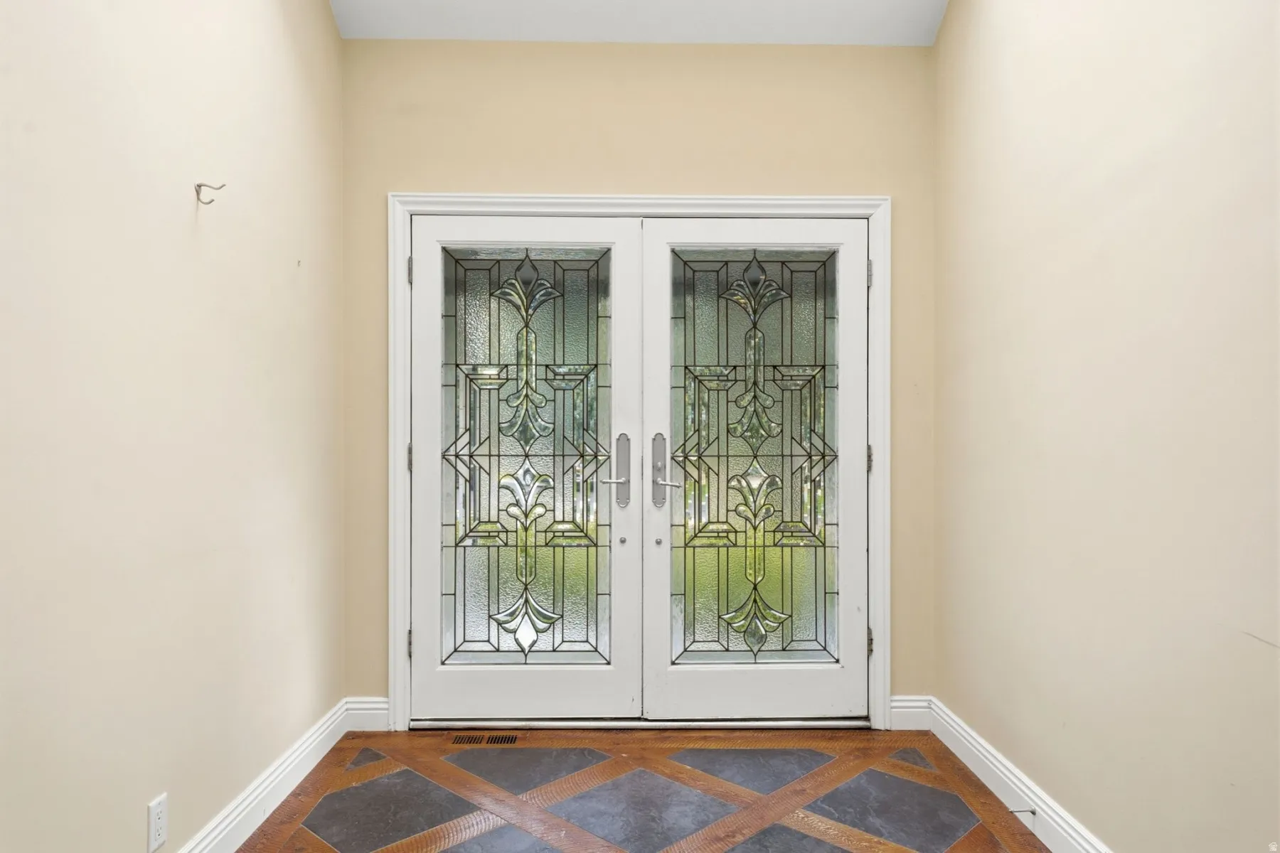 Entryway featuring decorative glass double doors and patterned floor tiling