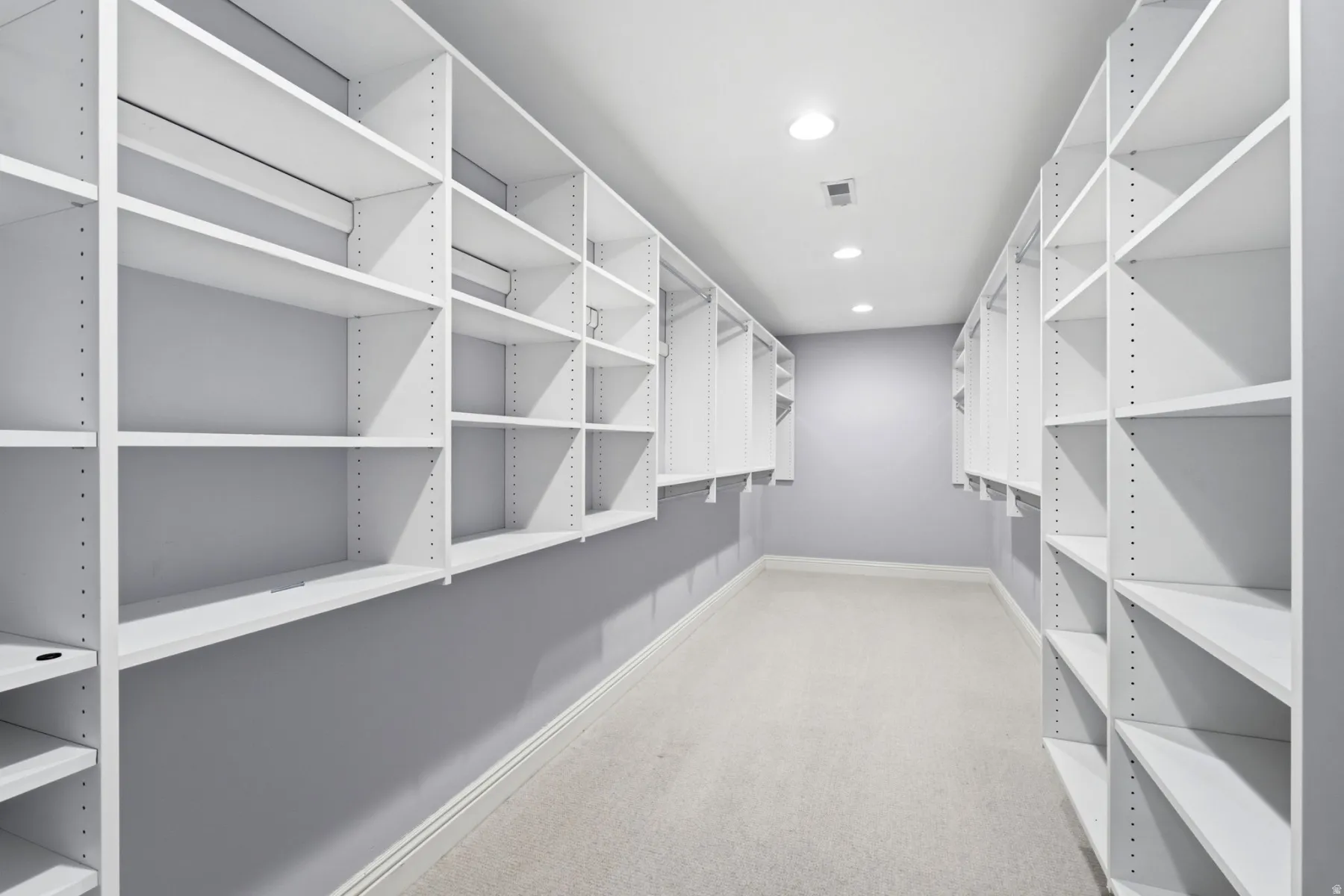Walk-in closet featuring extensive built-in shelving, hanging rods, recessed lighting, and carpeting