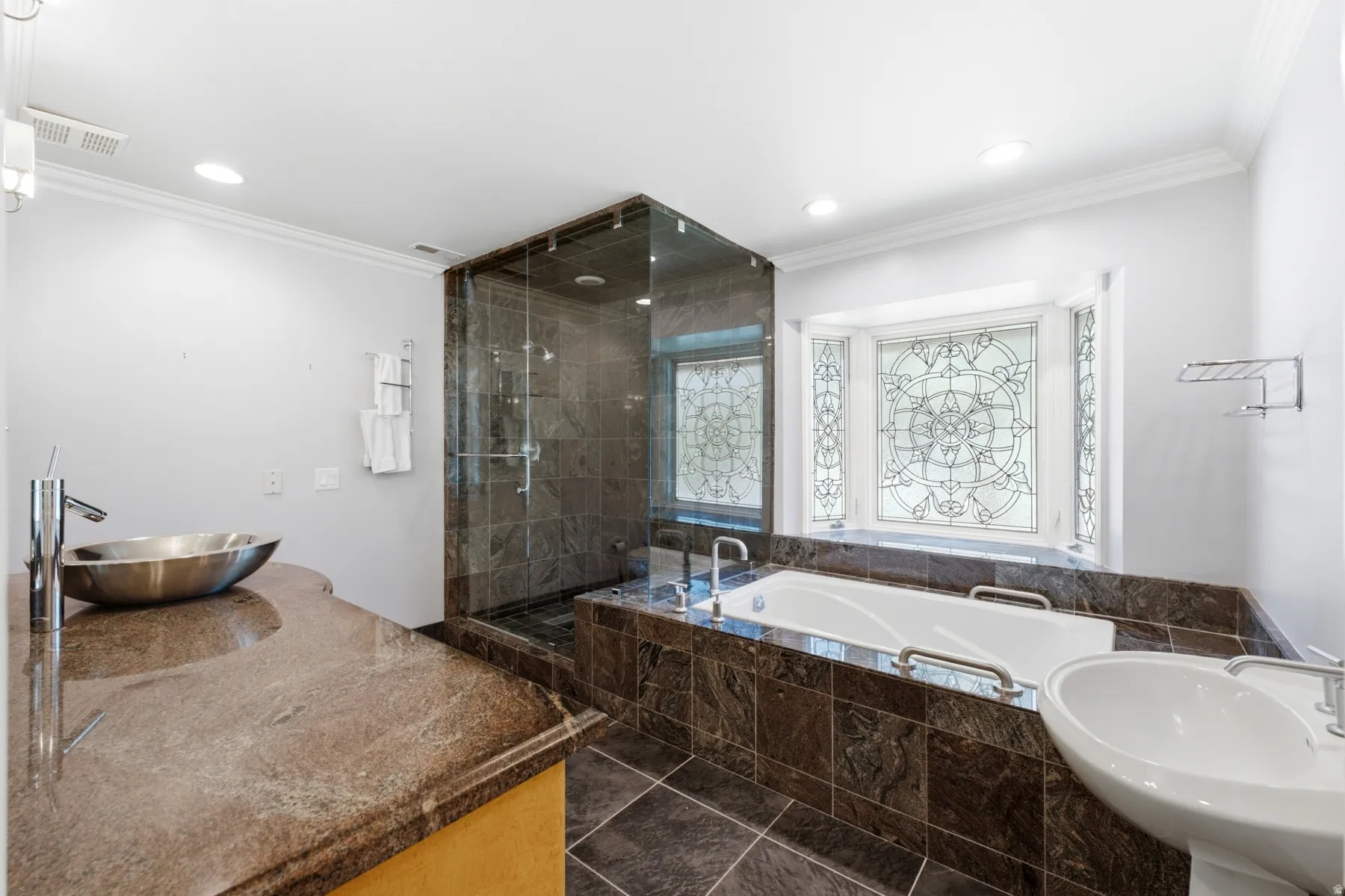 Walk-in shower with glass enclosure, built-in bathtub, ornamental stained glass window, and vessel sink with a stone countertop