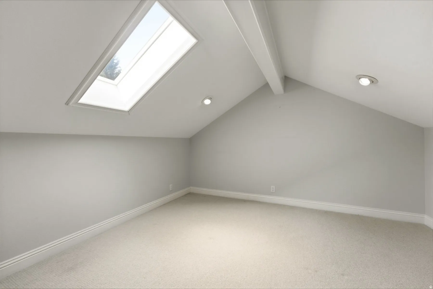 Vaulted ceiling with exposed beam, recessed lighting, skylight, and carpeting