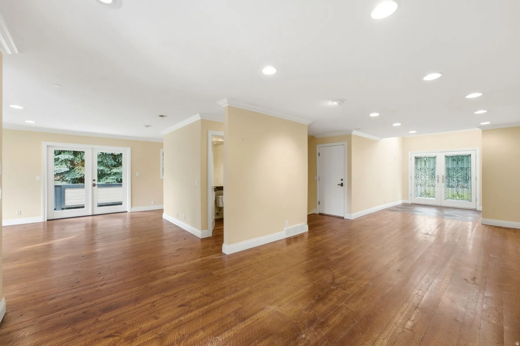 Wood-finish flooring throughout, recessed lighting, crown molding, and multiple sets of French doors