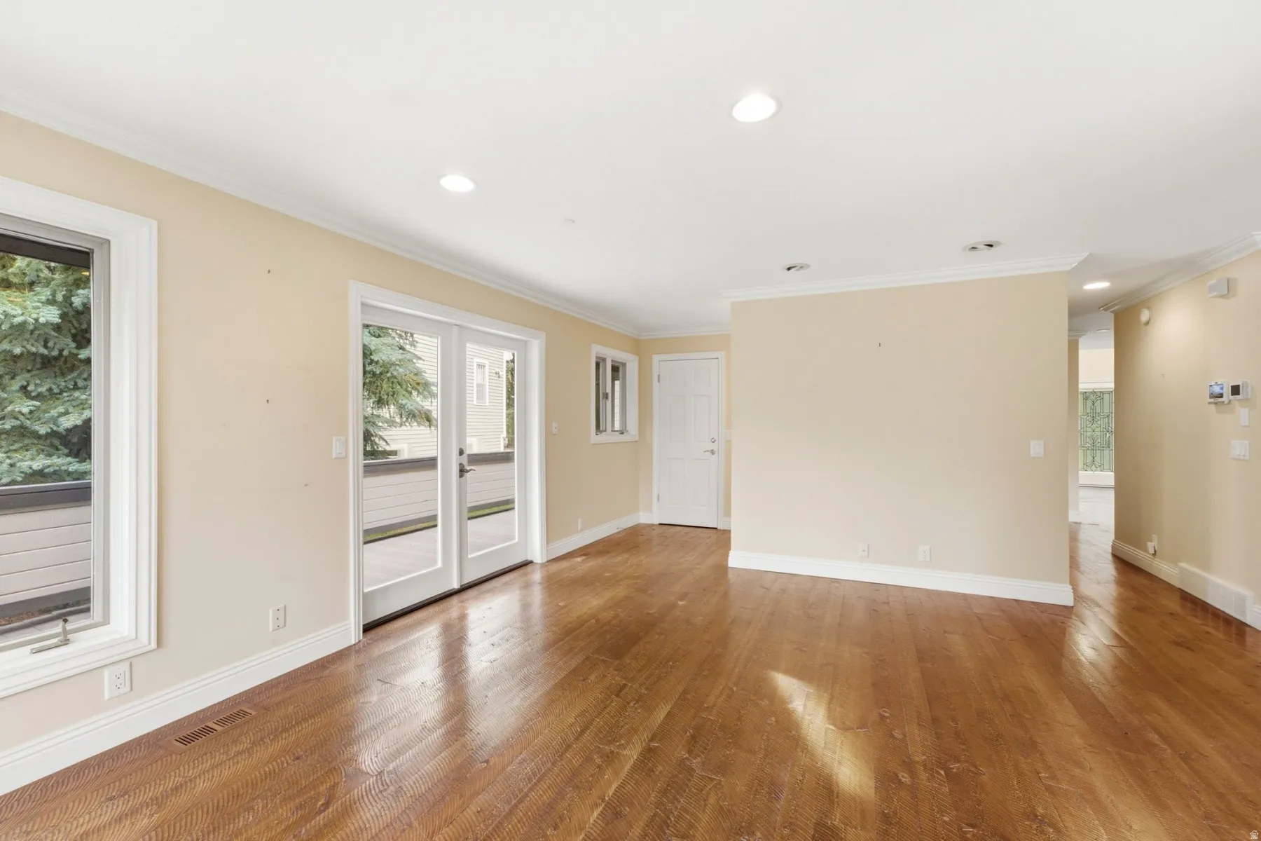 Wood-finish flooring throughout, recessed ceiling lights, white crown molding, and white trim
