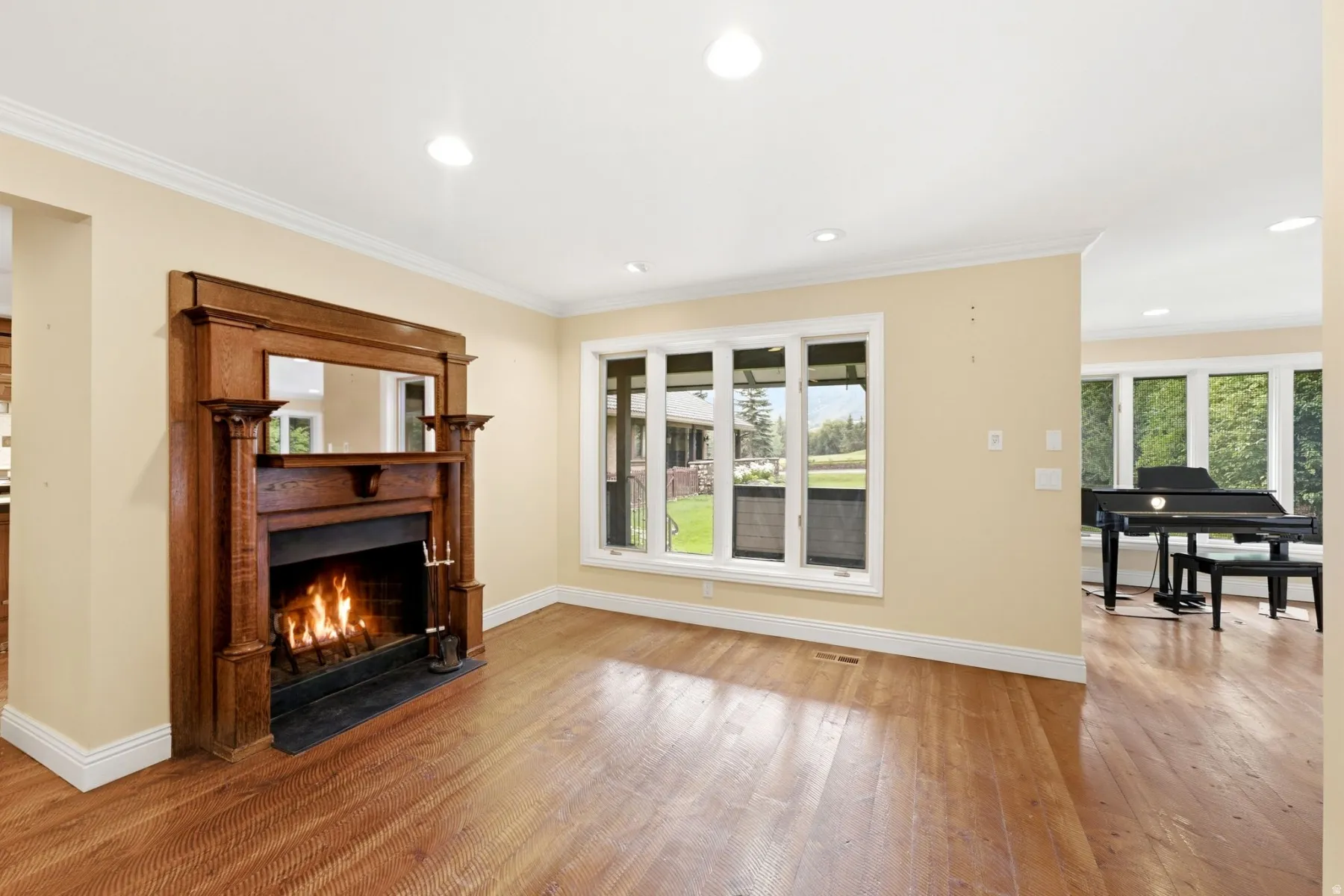 Hardwood flooring, crown molding, recessed lighting, wood-surround fireplace, and large windows