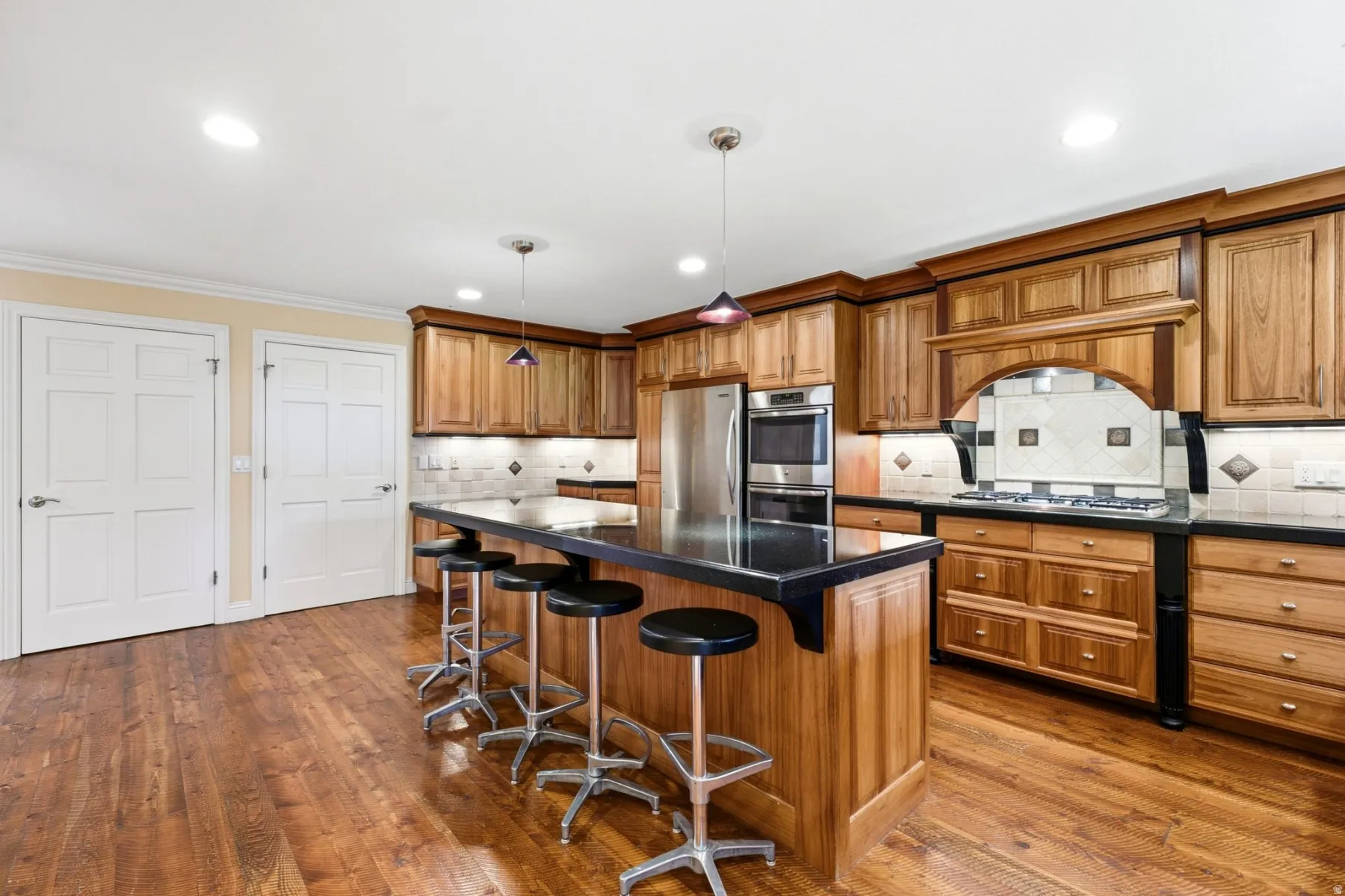 Wood-finish flooring, recessed lighting, and a kitchen island with dark countertops