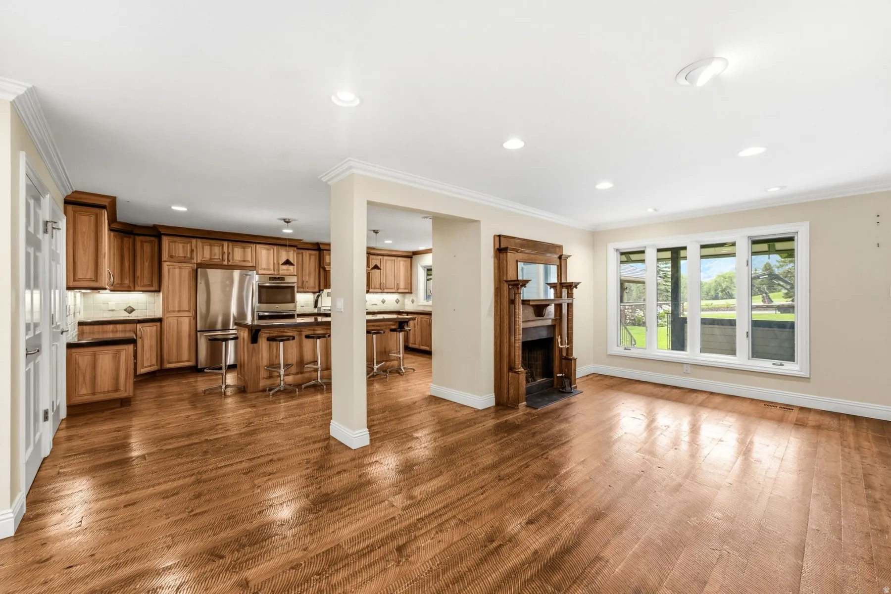 Hardwood flooring, wood cabinetry, stainless steel appliances, built-in fireplace with wood surround, and bay windows