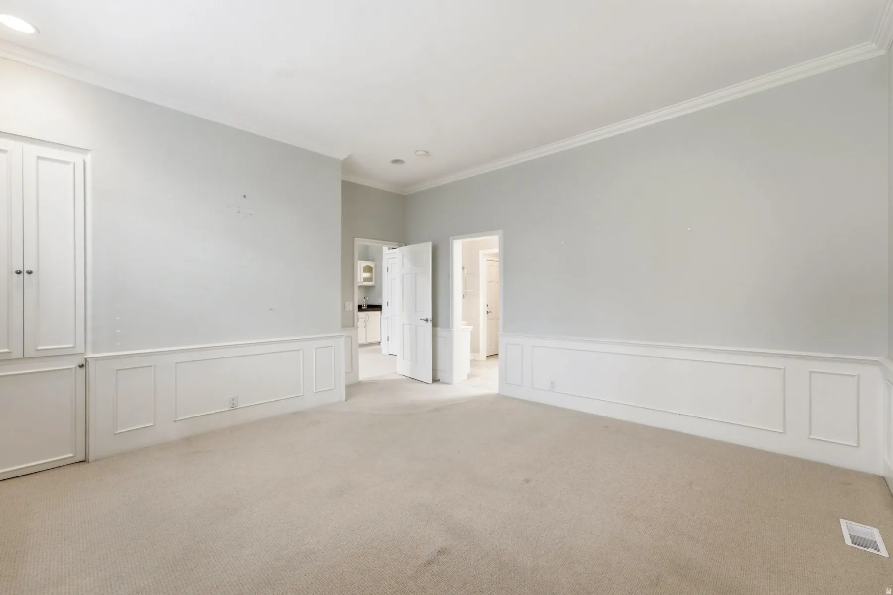 Recessed lighting, built-in cabinetry, crown molding, wainscoting, and carpet flooring