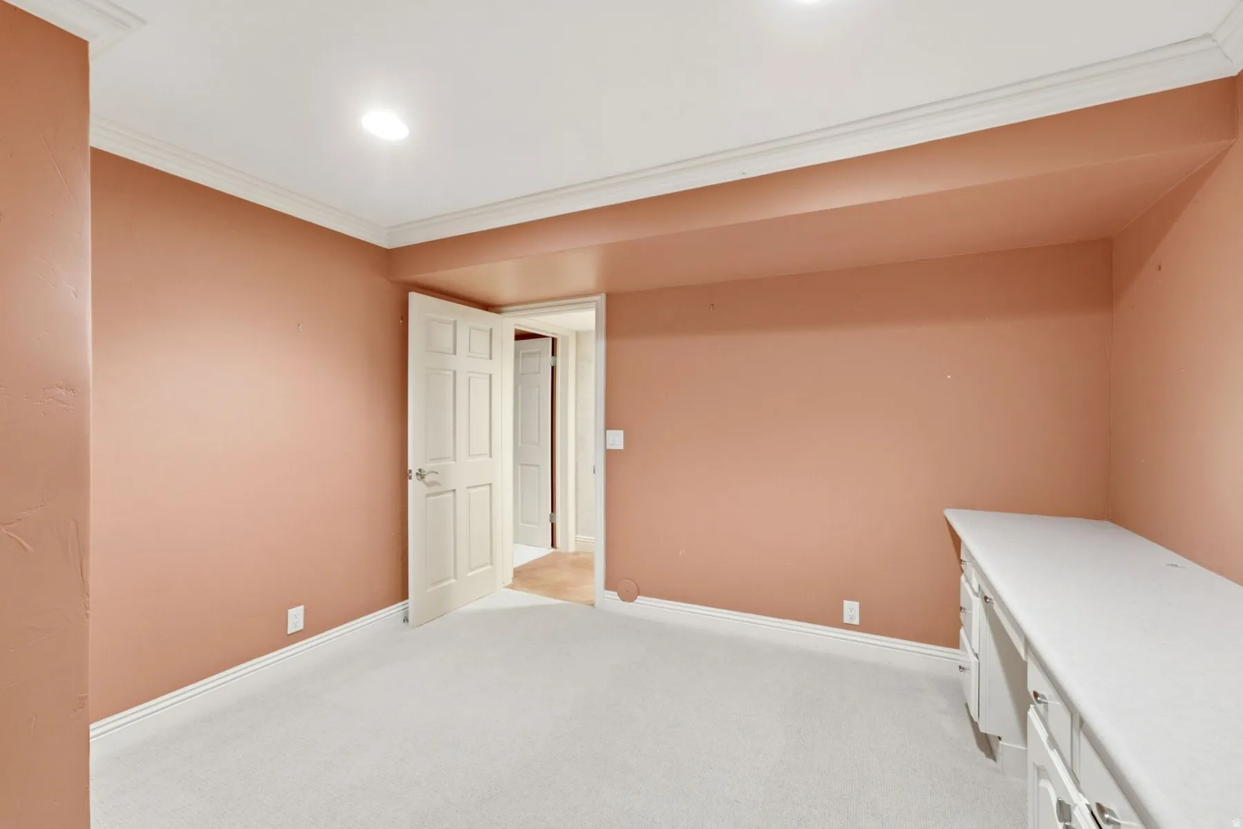 Recessed lighting, crown molding, paneled interior door, built-in desk, and carpeted flooring