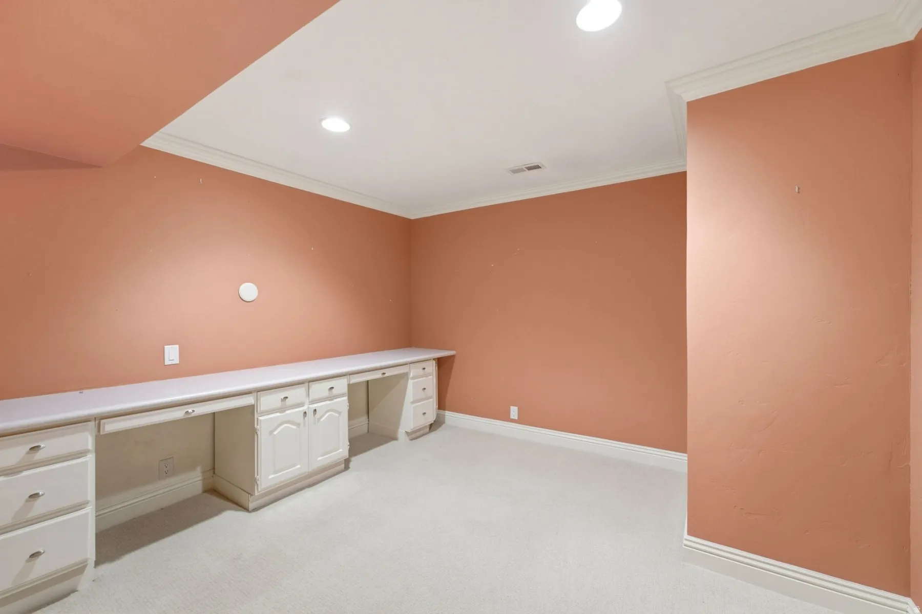 Built-in desk cabinetry with multiple workstations, recessed lighting, crown molding, and carpet flooring