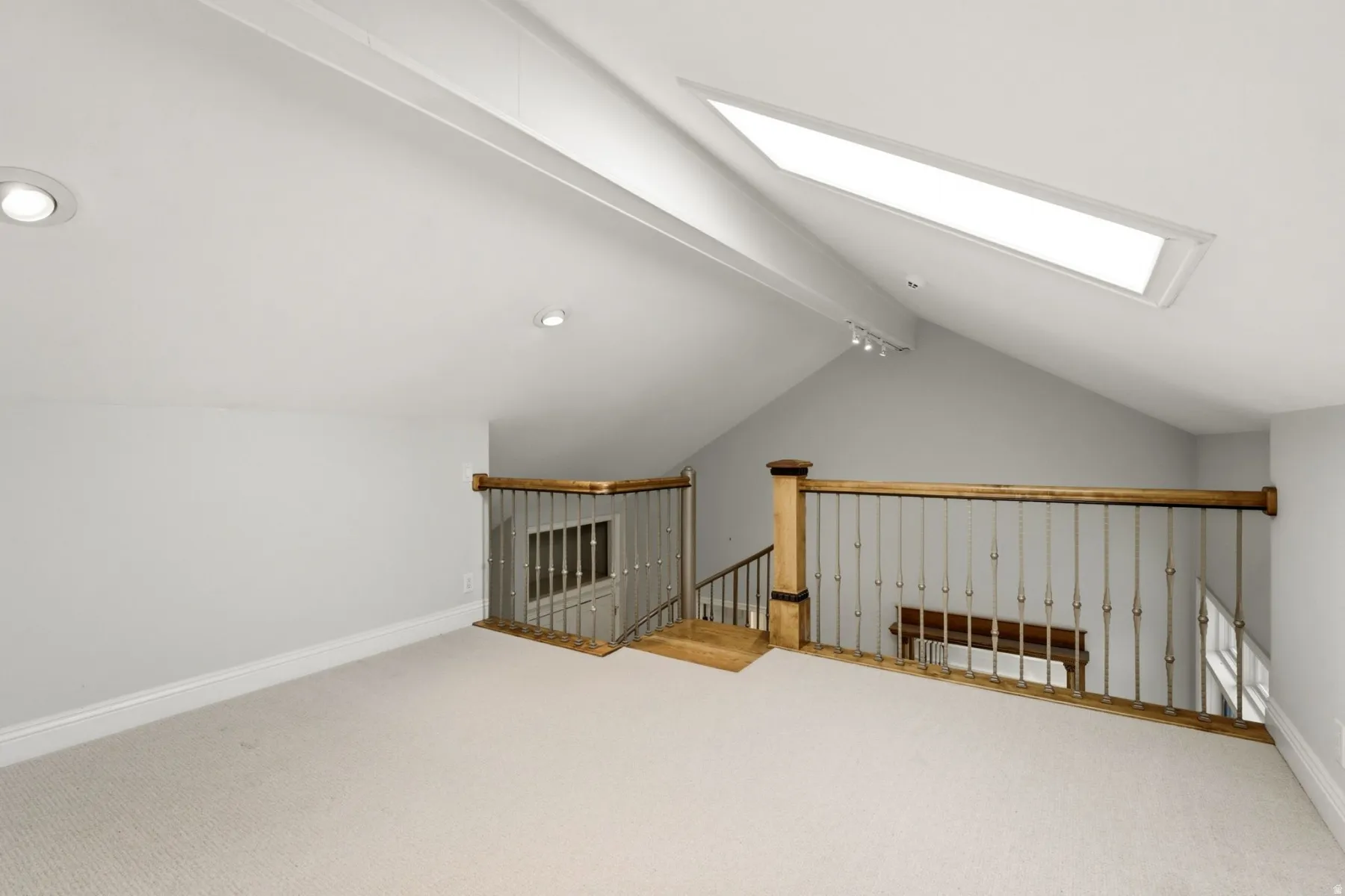 Carpeted loft space featuring an angled ceiling, recessed lighting, and a skylight